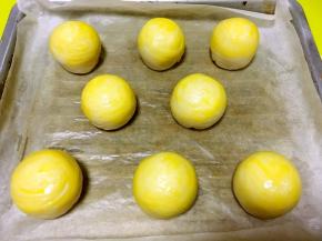 烤箱预热180度，烤盘铺油纸，将整理好的蛋黄酥放在烤盘上，取一颗蛋黄打散，用刷子均匀的刷上一层蛋黄液在蛋黄酥表层