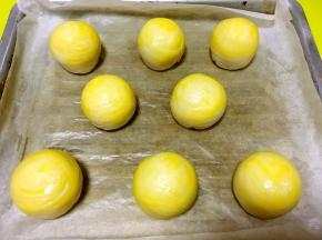 烤箱预热180度，烤盘铺油纸，将整理好的蛋黄酥放在烤盘上，取一颗蛋黄打散，用刷子均匀的刷上一层蛋黄液在蛋黄酥表层