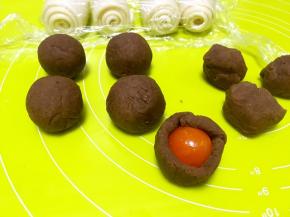 用手掌将豆沙馅压扁包裹上咸蛋黄，用虎口一点点向上推面团，收好收口，搓圆