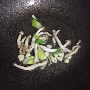 锅内热油倒葱姜蒜蘑菇翻炒出香味