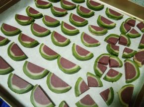 然后再对半切开即成为西瓜形状。撒上黑芝麻，挨个按一遍，让芝麻嵌入面团中。放入175度预热好的烤箱，烤15分钟，后五分钟火力调低5度，并且加盖锡纸，防止上色。