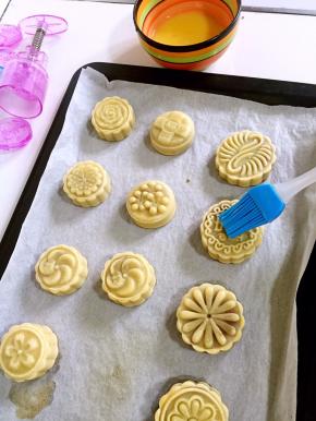 5分钟后出炉，硅胶刷先在碗壁上刮去多余的蛋液，再在月饼表面花纹上薄薄的刷一层蛋液。（不要刷的太多，要不然蛋液多了月饼表面的花纹会模糊。）