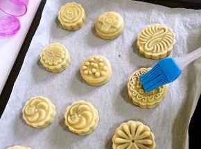 5分钟后出炉，硅胶刷先在碗壁上刮去多余的蛋液，再在月饼表面花纹上薄薄的刷一层蛋液。（不要刷的太多，要不然蛋液多了月饼表面的花纹会模糊。）