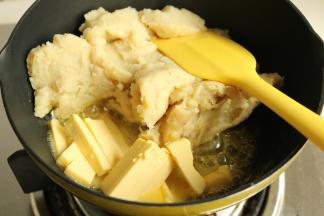 土豆泥先放入不粘锅内，超一下，去除一些水汽。然后放入黄油块，黄油不需要软化，直接放入锅里。