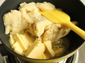 土豆泥先放入不粘锅内，超一下，去除一些水汽。然后放入黄油块，黄油不需要软化，直接放入锅里。