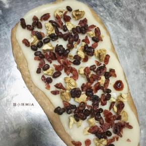 醒发好的面团擀开，铺上麻薯和果仁，从上往下卷起