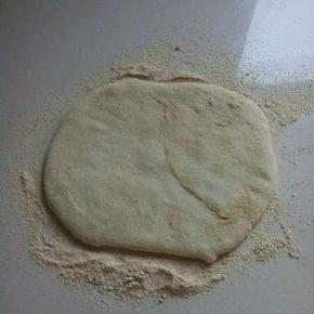 案板上放上一层黄豆粉，将其放上，上面再放上一层黄豆粉，用手压扁。