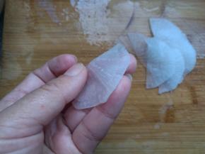 把萝卜片对折，一片压一片摆在盘子周围。