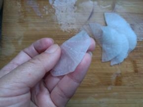 把萝卜片对折，一片压一片摆在盘子周围。