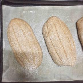 发酵好的面团表面喷水，撒高粉，用刀片割口