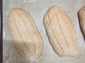 发酵好的面团表面喷水，撒高粉，用刀片割口