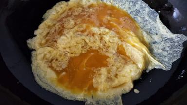 热锅冷油，油热后转中火倒入蛋液摊开