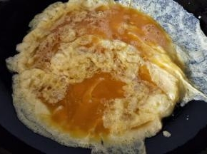 热锅冷油，油热后转中火倒入蛋液摊开