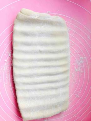 因为黄油较硬，很难擀动，所以，开始采用按压的方式，用擀面棍平行向下用力按。不要特别用力，擀成长方形