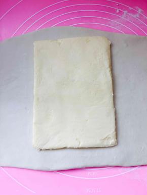 将主面团从冰箱里取出，擀成长方形，将黄油片放置于中间位置，面片的长度，够包裹住黄油片即可