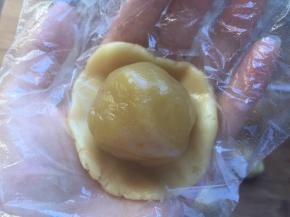 饼皮压扁，将莲蓉馅放在饼皮中间