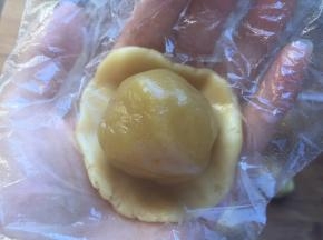 饼皮压扁，将莲蓉馅放在饼皮中间