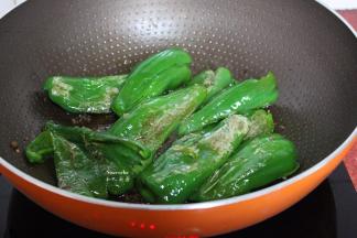 把青椒用锅铲一边压碎，一边翻炒至虎皮；