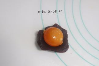 将称好的馅料搓圆压扁，我做了豆沙跟莲蓉两种馅料，放上咸蛋黄，用馅料把咸蛋黄包起，记住用虎口慢慢推，包裹均匀。最后揉圆。