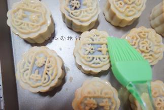 取出每次都晾凉5分钟，刷上蛋黄液+水（或全蛋液+水），记住表层蛋黄液别刷太多，最好用羊毛刷比较好控制蛋液量，蛋液只刷在花纹最上面凸出来的那部分就可以了，烤8分钟，再取出在周围和表面刷上蛋液。再烤8分钟出炉，晾凉。反复多次直到月饼烤至色泽金黄即可。不要时间超过8分钟，你可以多烤晾几次，因为烤的时间太长月饼皮变软支撑不了内部馅料的膨胀就会变形的，所以需要你勤快点换盘（我都是两个烤盘轮流做，取出来晾凉的时候把另外那个烤盘放进去烤，这样就不会浪费时间了），烤的时间自己把握，各家的烤箱温度都有差别。