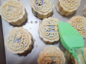 取出每次都晾凉5分钟，刷上蛋黄液+水（或全蛋液+水），记住表层蛋黄液别刷太多，最好用羊毛刷比较好控制蛋液量，蛋液只刷在花纹最上面凸出来的那部分就可以了，烤8分钟，再取出在周围和表面刷上蛋液。再烤8分钟出炉，晾凉。反复多次直到月饼烤至色泽金黄即可。不要时间超过8分钟，你可以多烤晾几次，因为烤的时间太长月饼皮变软支撑不了内部馅料的膨胀就会变形的，所以需要你勤快点换盘（我都是两个烤盘轮流做，取出来晾凉的时候把另外那个烤盘放进去烤，这样就不会浪费时间了），烤的时间自己把握，各家的烤箱温度都有差别。