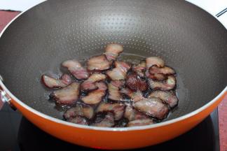 热锅倒油，小火煎腊肉，煎至微黄；