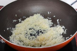 锅中放油，把腌制好的生米倒入翻炒至半透明状；