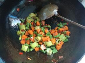 下入焯熟的胡萝卜丁和豇豆丁，翻炒均匀。