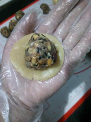 取一面团手掌心中按扁，放入五仁内馅。