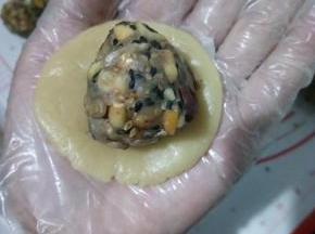 取一面团手掌心中按扁，放入五仁内馅。