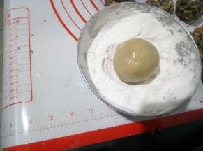 利用左手虎口慢慢往上推，把内馅包住，收口滚圆后在面粉里滚一下。