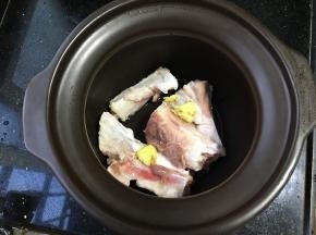 泡好的骨头反复清洗之后放入煲汤锅，拍两块姜进去