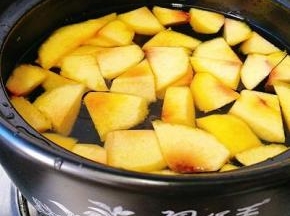 采用砂锅，将黄桃、冰糖、水放在一个无油的锅中煮开。