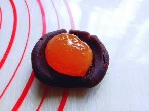 取一块豆沙馅，将蛋黄包起来。我的月饼磨具是50g的，所有我的月饼馅是30g，月饼皮是20g。