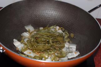 五花肉微黄，把肥肉的油炒出来，加入切好的酸辣椒；