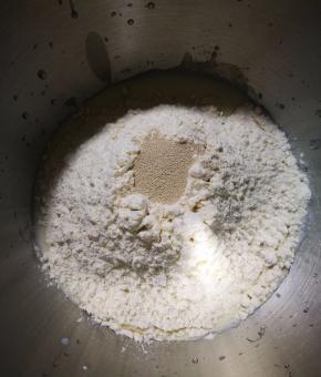 将材料中除黄油以外的材料按下层液体，中层粉体，上层酵母的顺序放入厨师机中，先低档开始揉面，揉到光滑面团时加入软化的黄油，改用中档继续揉面。