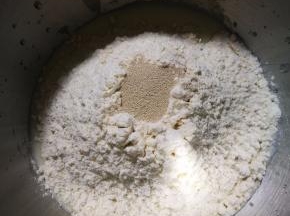 将材料中除黄油以外的材料按下层液体，中层粉体，上层酵母的顺序放入厨师机中，先低档开始揉面，揉到光滑面团时加入软化的黄油，改用中档继续揉面。