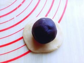 取一块切好的面团，用手掌心压扁，再用擀面杖擀薄，包上蜜豆蛋黄馅，虎口手法包起来，收口朝下，这样步骤及手法全部做完。