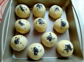 刷好蛋液的蛋黄酥上面撒上撒上黑芝麻，撒好芝麻后还可以再刷一层蛋液。