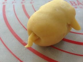 将猪屁股向里压按一下，然后用小小的面团搓长，沾点水，粘在猪屁股上面。