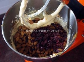 将保温中的杏仁粒和蔓越莓干加入搅拌缸中，用橡皮刮刀拌均。