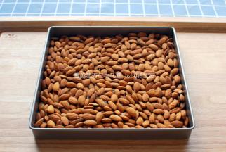 杏仁粒倒入烤盘，放入上下火150度预热好的烤箱中层烘烤20分钟，烤熟后温度降至上下火100度进行保温。