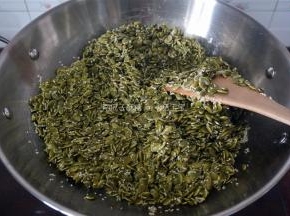 将保温中的芝麻南瓜子全部倒入糖浆中，翻炒均匀。