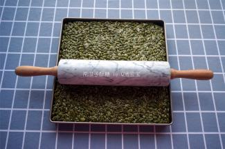 11寸不粘正方形烤盘垫上硅胶垫，将拌匀的食材放入烤盘中，用大理石走锤擀面杖将其压紧。