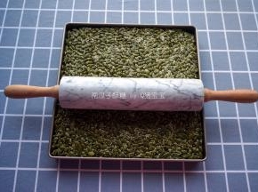 11寸不粘正方形烤盘垫上硅胶垫，将拌匀的食材放入烤盘中，用大理石走锤擀面杖将其压紧。