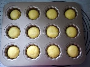 捏紧收口，滚圆，收口朝下放入可露丽12连模中，放温暖处进行二次发酵。