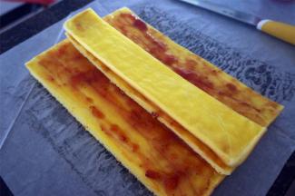 待蛋糕体冷却至温温的状态时，将蛋糕体平均分成5份，左右各裁出五分一，抹上果酱后，将其放置在蛋糕体中央。