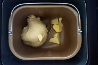 将黄油除外的面团原料放入面包机，选择和面程序，揉至第一个程序结束后加入黄油，再次启动一个和面程序至面团可拉出不容易破的膜。