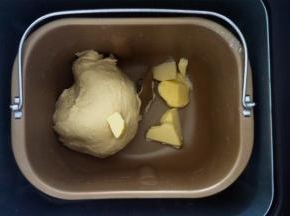 将黄油除外的面团原料放入面包机，选择和面程序，揉至第一个程序结束后加入黄油，再次启动一个和面程序至面团可拉出不容易破的膜。