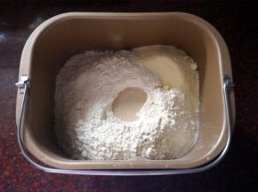 将黄油除外的食材按照先液体后固体的顺序放入面包机，启动揉面程序揉面20分钟。